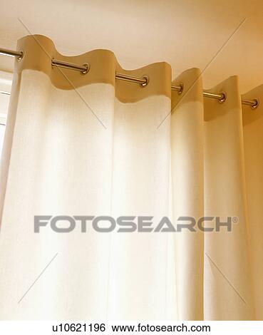 Stock Photograph - Close-up of cream curtains on metal pole. Fotosearch