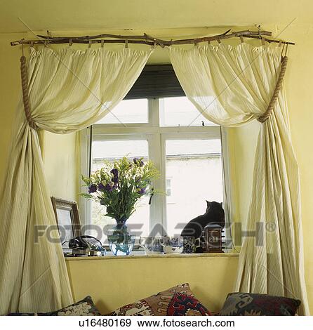Stock Photo - Close-up of cream curtains on twig pole. Fotosearch