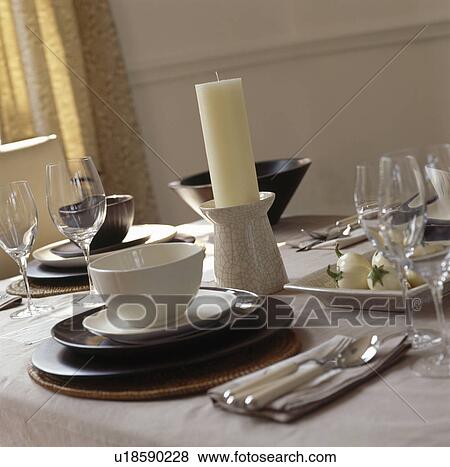 Stock Photo - Close-up of dining table with cream and brown crockery and large candle in ceramic holder&#13; &#10; &#13; &#10; &#13; &#10; &#13; &#10;. Fotosearch