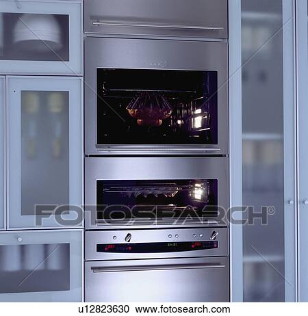 Stock Image - Close-up of double stainless steel oven between opaque glazed cupboard doors&#13; &#10; &#13; &#10; &#13; &#10; &#13; &#10; &#13; &#10; &#13; &#10;. Fotosearch