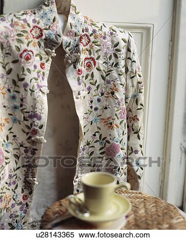 Close-up of embroidered cream jacket on door behind table with yellow cup View Large Photo Image Stock Photography - Close-up of embroidered cream jacket on door behind table with yellow cup. Fotosearch
