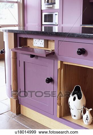 Close-up of false drawer open to reveal electric plug sockets in modern purple kitchen with ceramic vases in alcove View Large Photo Image Stock Photo - Close-up of false drawer open to reveal electric plug sockets in modern purple kitchen with ceramic vases in alcove. Fotosearch