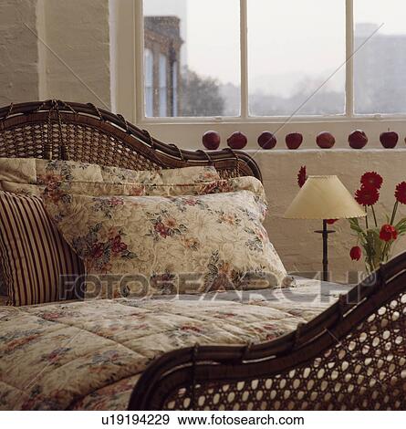 Stock Photo - Close-up of floral pillows and quilt on cane bed. Fotosearch