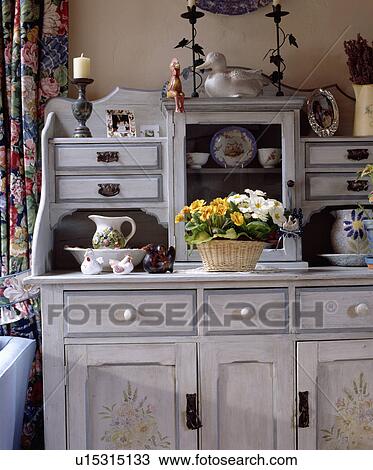 Stock Image - Close-up of grey dressser with basket of primroses and stencilled flowers. Fotosearch