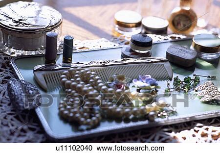 Stock Image - Close-up of jewellery and silver comb on tray. Fotosearch