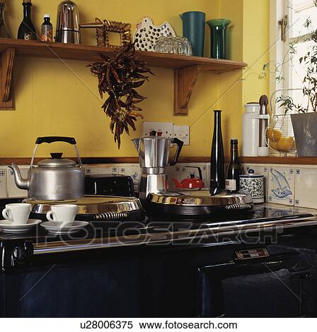 Stock Photography - Close-up of large stainless steel kettle and coffee pot on black Aga. Fotosearch