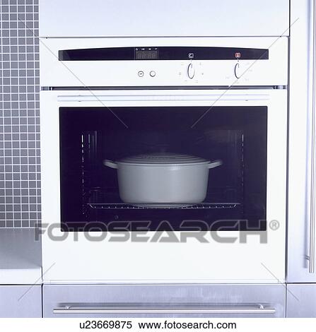Stock Photography - Close-up of large white casserole dish in white oven&#13; &#10; &#13; &#10; &#13; &#10; &#13; &#10; &#13; &#10;. Fotosearch