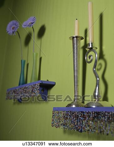 Stock Image - Close-up of metal candlesticks on blue beaded shelf. Fotosearch