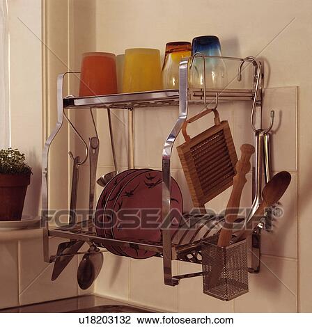 Stock Image - Close-up of metal plate rack with colourful glasses and utensils. Fotosearch