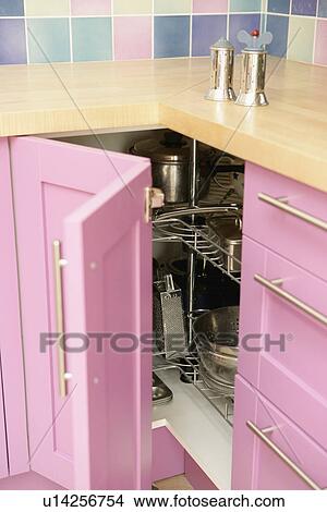 Picture - Close-up of metal salt+pepper mills above open pink folding door on kitchen storage cupboard . Fotosearch