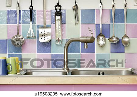 Close-up of metal utensils on multicoloured pastel wall tiles above stainless steel mixer tap and double sink View Large Photo Image Stock Photography - Close-up of metal utensils on multicoloured pastel wall tiles above stainless steel mixer tap and double sink. Fotosearch