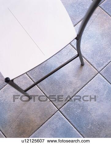 Stock Photo - Close-up of modern chair on grey floor tiles. Fotosearch