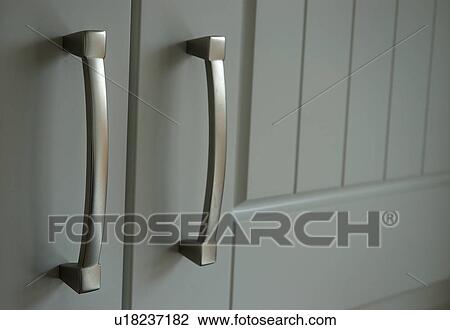 Stock Image - Close-up of modern stainless steel handles on grey door. Fotosearch