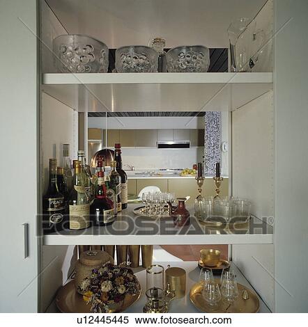 Close up of open shelves with bottles of alcohol and glass bowls and view of kitchen View Large Photo Image Stock Photography - Close up of open shelves with bottles of alcohol and glass bowls and view of kitchen. Fotosearch