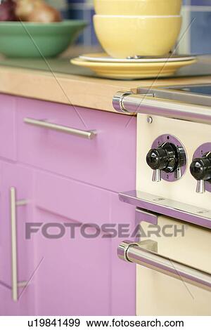 Stock Photo - Close-up of oven beside modern pink kitchen cupboard. Fotosearch