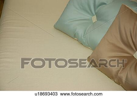 Stock Image - Close-up of pastel blue and brown silk cushions on cream linen. Fotosearch
