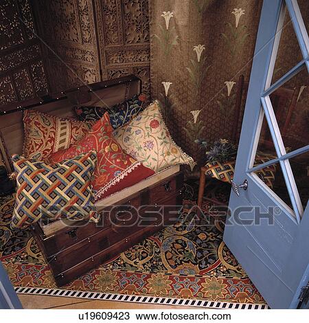 Stock Image - Close-up of patterned cushions in old wooden chest. Fotosearch