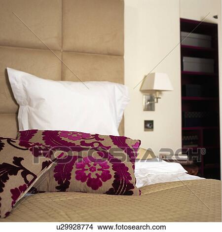 Picture - Close up of pink and beige cut velvet Designers Guild cushion and white pillow on cream bedspread. Fotosearch