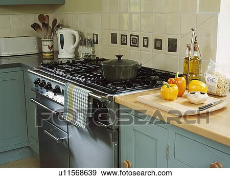 Close-up of range oven beside turquoise fitted cupboard with wood worktop and peppers on chopping board View Large Photo Image Stock Photo - Close-up of range oven beside turquoise fitted cupboard with wood worktop and peppers on chopping board. Fotosearch
