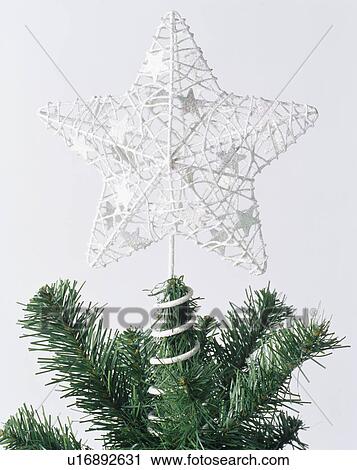 Stock Image - Close-up of silver wirework star on top of Christmas tree. Fotosearch