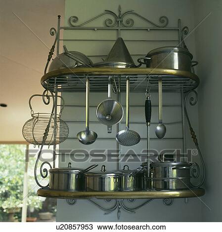 Stock Image - Close-up of stainless steel pans and utensils on ornate metal shelf unit. Fotosearch