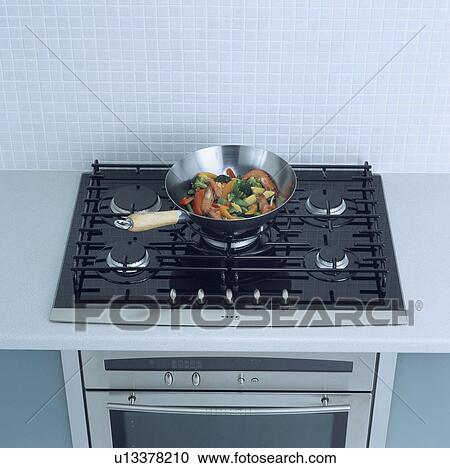 Close-up of stainless steel wok pan with vegetables on black gas hob in worktop above oven View Large Photo Image Stock Image - Close-up of stainless steel wok pan with vegetables on black gas hob in worktop above oven . Fotosearch