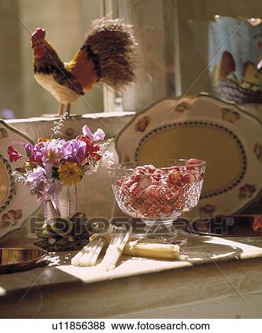 Stock Photo - Close-up of strawberries in glass dish beside small flower arrangement. Fotosearch