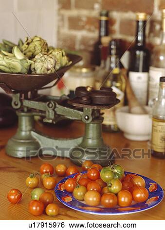 Stock Photograph - Close-up of traditional green weighing scales and red tomatoes on blue plate . Fotosearch