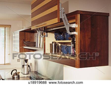 Close-up of walnut and maple veneer fitted cupboard with door raised on levers View Large Photo Image Stock Photo - Close-up of walnut and maple veneer fitted cupboard with door raised on levers. Fotosearch