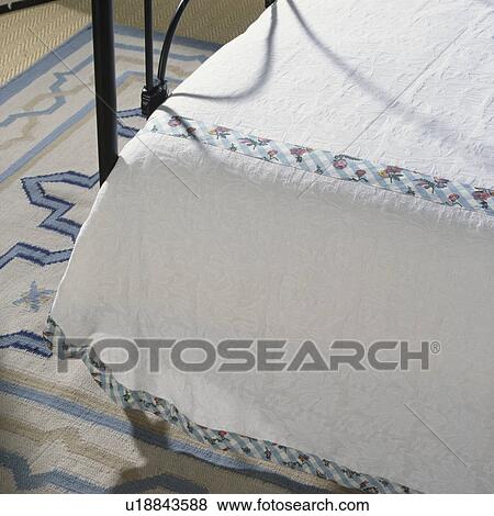 Stock Photo - Close-up of white linen bedcover trimmed with floral ribbon. Fotosearch
