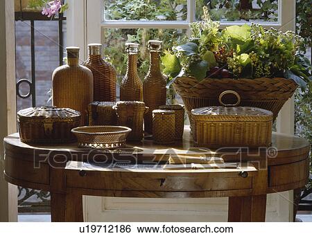 Stock Photograph - Close-up of wicker bottles and baskets on antique table. Fotosearch