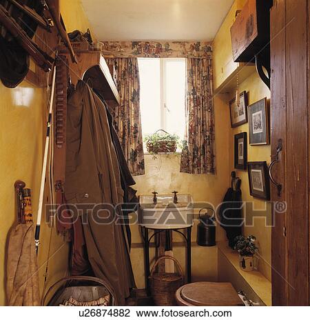 Coats on rack beside small old basin in yellow cloakroom with fishing equipment View Large Photo Image Stock Image - Coats on rack beside small old basin in yellow cloakroom with fishing equipment. Fotosearch