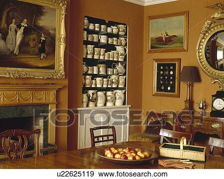 Stock Photo - Collection of antique china jugs and tankards on alcove shelves in terracotta county dining room . Fotosearch