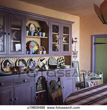 Collection of colourful modern pottery on purple dresser in peach dining room View Large Photo Image Stock Photo - Collection of colourful modern pottery on purple dresser in peach dining room. Fotosearch