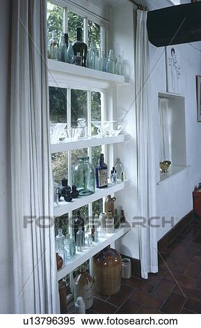 Collection of old glass bottles on shelves on white window View Large Photo Image Stock Photography - Collection of old glass bottles on shelves on white window. Fotosearch