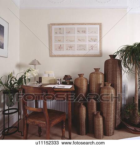 Collection of tall wicker bottle sculptures in neutral study with wooden desk and chair View Large Photo Image Stock Image - Collection of tall wicker bottle sculptures in neutral study with wooden desk and chair. Fotosearch