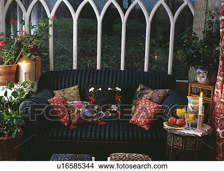 Colourful cushions on black sofa against windows in conservatory at night View Large Photo Image Picture - Colourful cushions on black sofa against windows in conservatory at night. Fotosearch