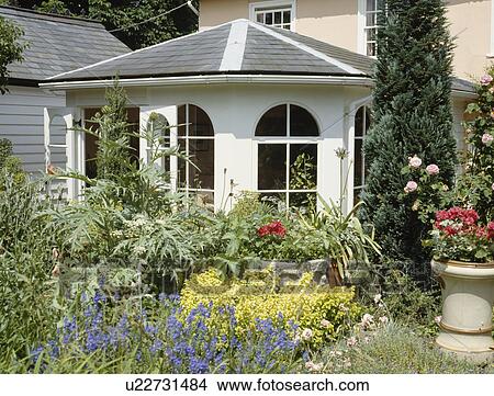 Colourful summer-flowering perennials in garden in front of traditional conservatory extension View Large Photo Image Picture - Colourful summer-flowering perennials in garden in front of traditional conservatory extension. Fotosearch