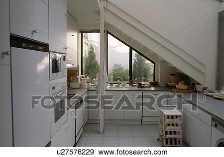 Compact modern white attic kitchen with view of roof garden through window View Large Photo Image Stock Photo - Compact modern white attic kitchen with view of roof garden through window. Fotosearch