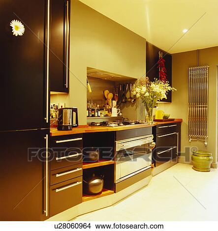 Compact yellow kitchen with dark brown fitted cupboards and stainless steel vertical wall-mounted radiator View Large Photo Image Picture - Compact yellow kitchen with dark brown fitted cupboards and stainless steel vertical wall-mounted radiator. Fotosearch