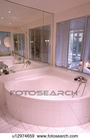 Contemporary white mirrored bathroom with corner bath View Large Photo Image Stock Photo - Contemporary white mirrored bathroom with corner bath . Fotosearch