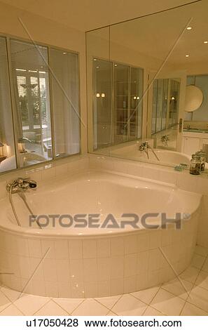 Contemporary white mirrored bathroom with corner bath View Large Photo Image Stock Photo - Contemporary white mirrored bathroom with corner bath . Fotosearch