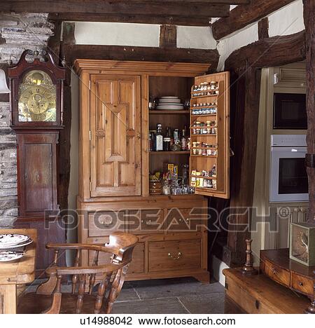Cottage kitchen with longcase clock beside large carved antique storage cupboard with door open View Large Photo Image Stock Image - Cottage kitchen with longcase clock beside large carved antique storage cupboard with door open . Fotosearch
