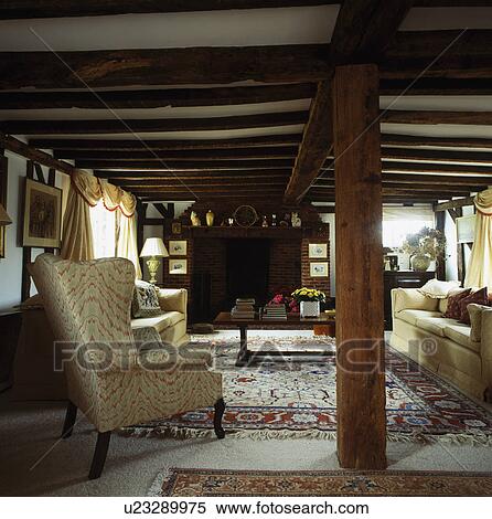Cottage livingroom with low beamed ceiling and cream sofa and armchair beside large upright beam View Large Photo Image Stock Photography - Cottage livingroom with low beamed ceiling and cream sofa and armchair beside large upright beam. Fotosearch