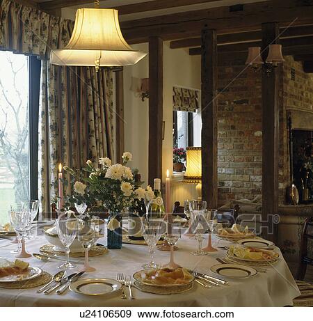 Stock Photo - Country dining room with white cloth on table set for lunch with glasses and silver cutlery. Fotosearch