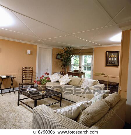 Stock Photography - Cream corduroy sofas in pale terracotta traditional living room. Fotosearch