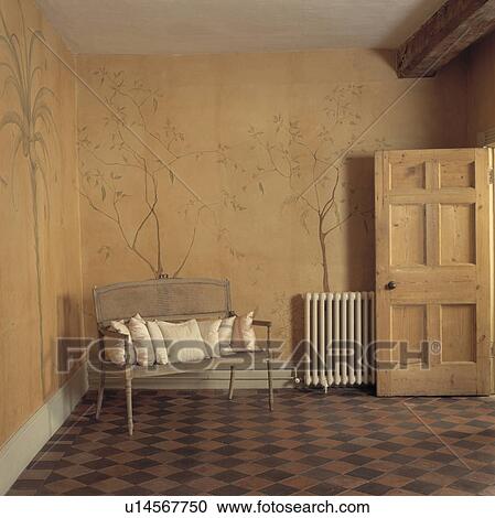 Stock Image - Cream cushions on small 18th century sofa in neutral hall with painted mural on walls and red+black floor tiles. Fotosearch