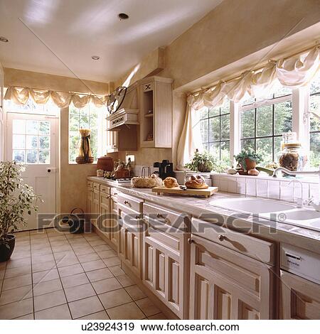 Cream Drapes In Neutral Kitchen With Cream Tiled Floor Stock Photo
