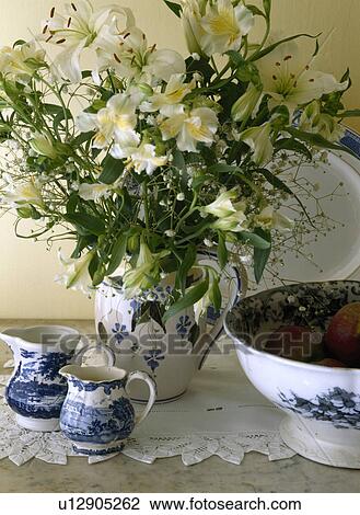 Cream lilies in old blue patterned jug on table with small blue and white jugs and bowl View Large Photo Image Stock Image - Cream lilies in old blue patterned jug on table with small blue and white jugs and bowl. Fotosearch