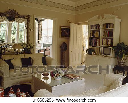Stock Photography - Cream sofa and bookcase in traditional cream living room. Fotosearch